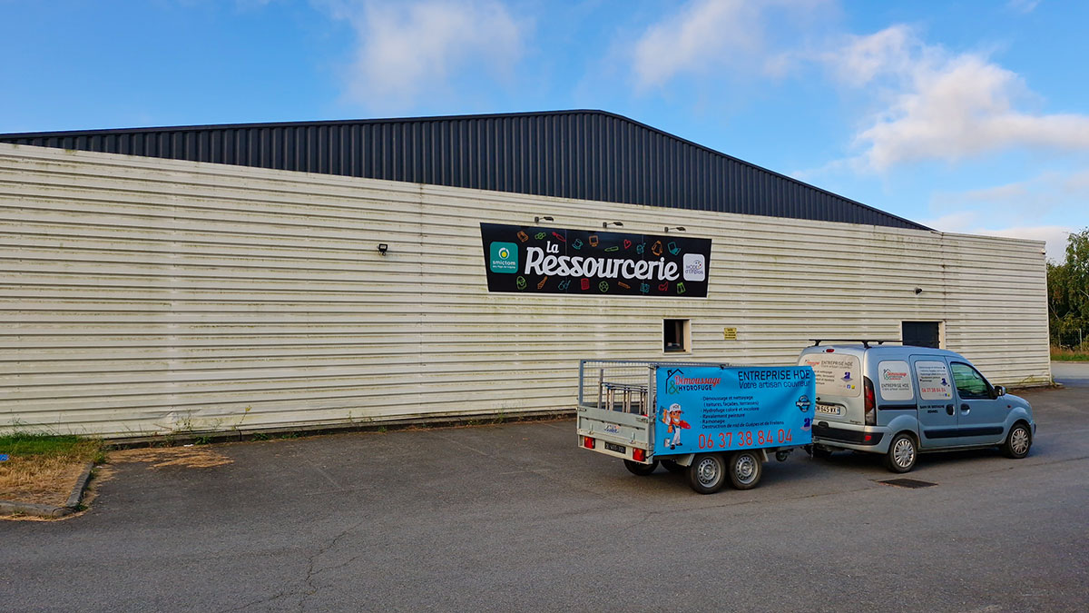 Photo du bâtiment de la Ressourcerie à Janzé avant nettoyage par l'entreprise HDE. Avec les véhicules d'intervention de HDE-Démoussage,ramonage,rénovation toiture et façade. à l'avant plan.